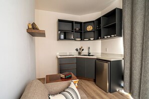 A compact kitchen with built-in shelves, a dining area with a table and books, and a modern refrigerator. - Laurelian 5 · Lior · Private suite near downtown (Oaxaca de Juárez)