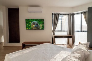 Een hotelkamer met een bed, een bureau, een raam met gordijnen en een schilderij aan de muur.