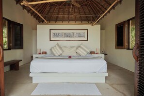 A bedroom with a bed, pillows, a bedside table, a lamp, and a framed picture on the wall.