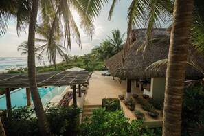 A resort with a pool, lounge area, and thatched-roof structures. - Private beachfront estate in the Oaxacan jungle (Puerto Escondido)