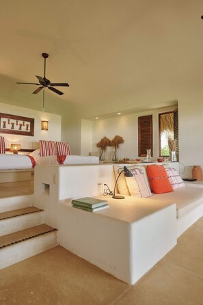 A modern living room with a sofa, a coffee table, a ceiling fan, and a staircase leading to an upper level. - Private beachfront estate in the Oaxacan jungle (Puerto Escondido)