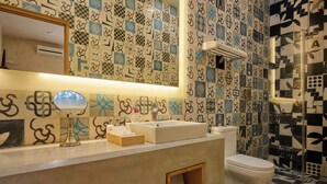 Un bagno con una parete rivestita di piastrelle decorate, un lavabo con specchio e un water.