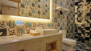 Ein Badezimmer mit gefliestem Wandmuster, einem Waschbecken mit Spiegel und einer Toilette.