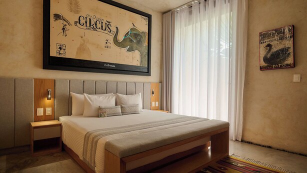 Una camera da letto con un letto grande, una testiera, comodini, un'opera d'arte appesa al muro e una finestra con tende.