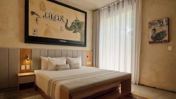 Ein Schlafzimmer mit einem großen Bett, einem Kopfteil, Nachttischen, einem Wandbild und einem Fenster mit Vorhängen.