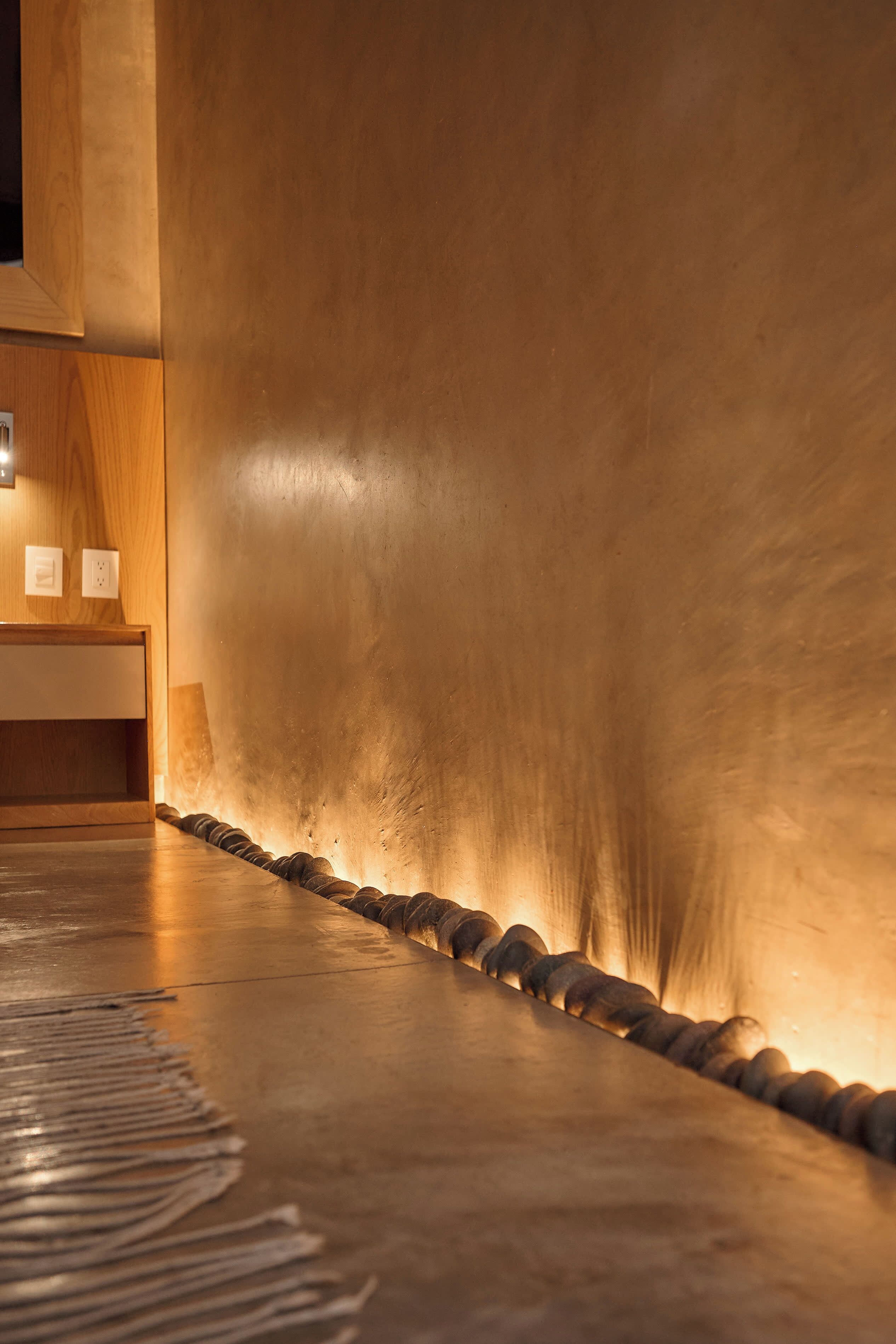 A modern interior with a wooden reception desk and a large, textured wall.