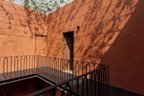Ein Balkon mit Metallgeländer, einer Holztür und einer Wand mit Schatten.