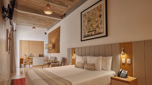 Una habitación de hotel con una cama grande, un escritorio, una silla y una obra de arte en la pared.