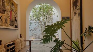 A hallway with a bench, a potted plant, and a wall with a mural.