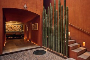 Een hotel lobby met een stenen vloer, een wand met cactussen en een trap.