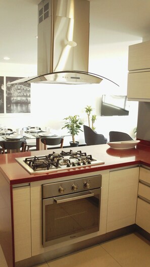 A modern kitchen with a gas stove, oven, and a stainless steel range hood.