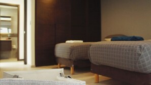 A hotel room with two beds, a wardrobe, and a suitcase on the floor.