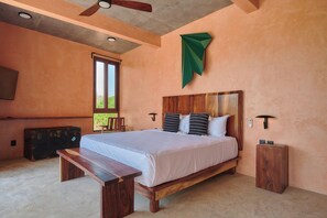A bedroom with a wooden bed, a bench, a suitcase, and a ceiling fan. - 5-bedroom house steps from the beach (Puerto Escondido)