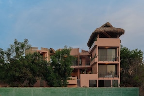 A multi-story building with a flat roof and a thatched roof on the top. - 5-bedroom house steps from the beach (Puerto Escondido)