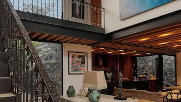 A spacious interior with a high ceiling, a staircase leading to a balcony, and a large wall mural.