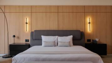 Een moderne slaapkamer met een groot bed, twee nachtkastjes en een bijzettafeltje met een lamp.