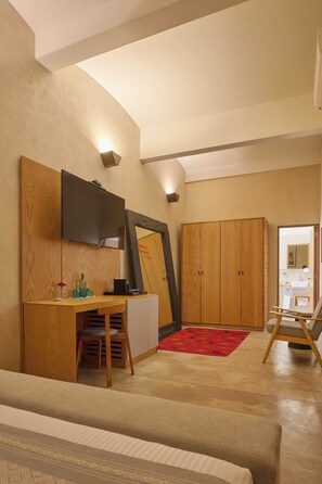 A room with a wooden desk, a chair, a television mounted on the wall, a wardrobe, and a red rug on the floor. - Artistic Boutique Hotel in Historic Oaxaca (Oaxaca de Juárez)