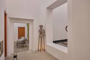 A minimalist interior with a sculpture, a wooden door, and a seating area. - Artistic Boutique Hotel in Historic Oaxaca (Oaxaca de Juárez)