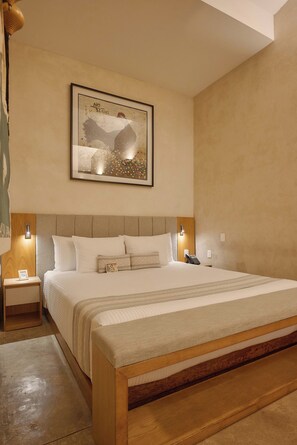 A hotel room with a large bed, a headboard, bedside tables, a wall-mounted artwork, and a nightstand with a phone. - Artistic Boutique Hotel in Historic Oaxaca (Oaxaca de Juárez)