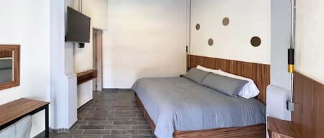 A bedroom with a bed, a desk, a TV, and a wall with circular decorations.
