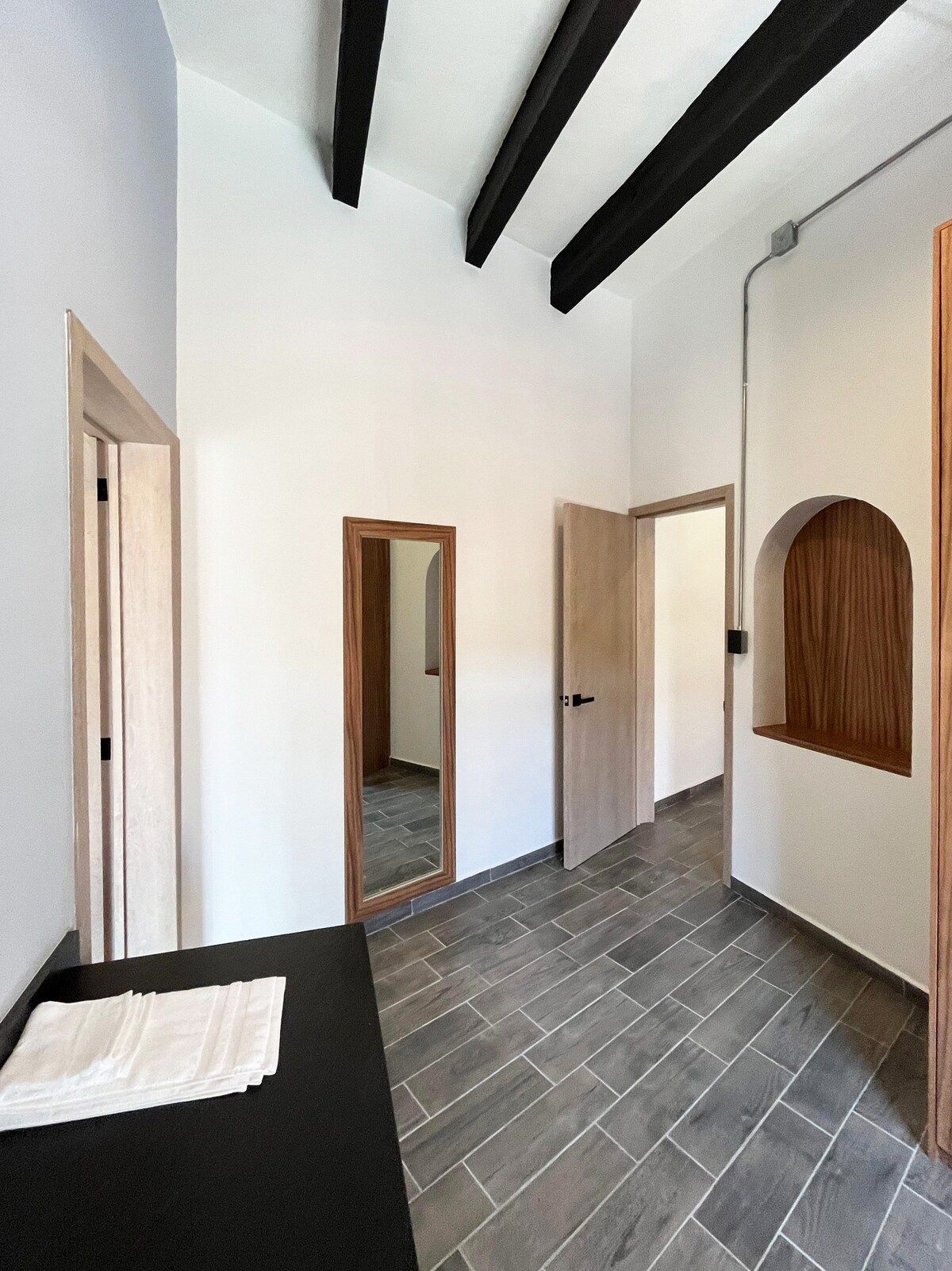 Corredor com um banco preto, portas de madeira e piso de azulejos.