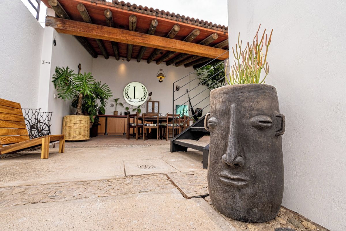 Un patio esterno con pavimento in pietra, mobili in legno, un grande vaso con motivo a volto e un soffitto piastrellato.