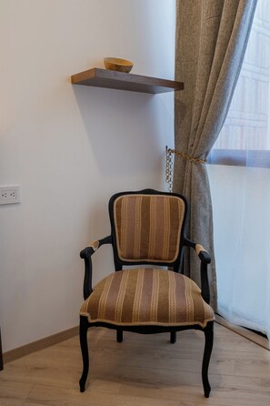 A chair with a striped cushion, a wooden shelf above it, and a power outlet on the wall. - Laurelian 8 · Eles · 2 BR Apt near downtown (Oaxaca de Juárez)