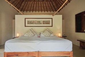 Ein Bett mit Holzrahmen, zwei Kissen, eine weiße Tagesdecke und zwei Bilderrahmen an der Wand.