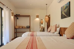 A hotel room with two beds, a wooden shelf with baskets, a radio, and a painting on the wall. - Casa Juliana · Private suite · Beachfront property (Puerto Escondido)