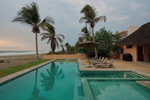 A pool area with lounge chairs and umbrellas, palm trees, and a beach view. - Casa Juliana · Private suite · Beachfront property (Puerto Escondido)