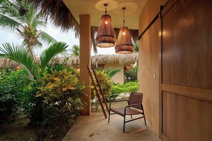 A tropical outdoor area with a wooden bench, hanging wicker lamps, and lush greenery. - Casa Juliana · Private suite · Beachfront property (Puerto Escondido)