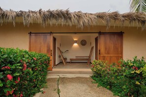A thatched-roof entrance with a bench and a ladder, surrounded by lush greenery. - Casa Juliana · Private suite · Beachfront property (Puerto Escondido)
