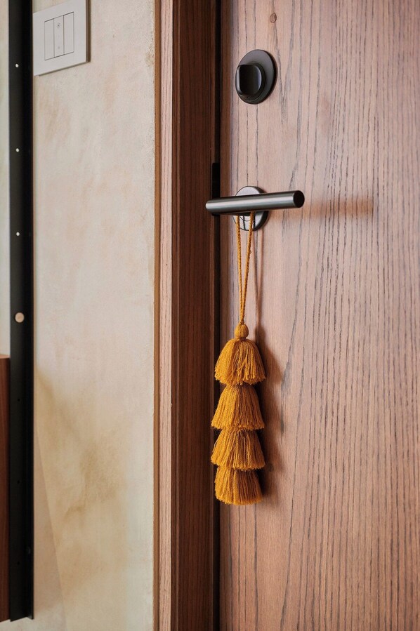 Una porta de fusta amb un pom negre, una mirallera i un pompons groc penjant d'una clau.