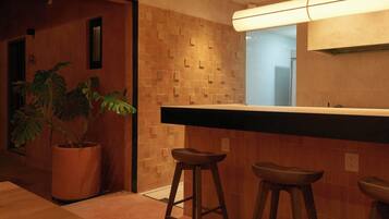 Une cuisine moderne avec un coin bar, des tabourets en bois et une plante en pot.
