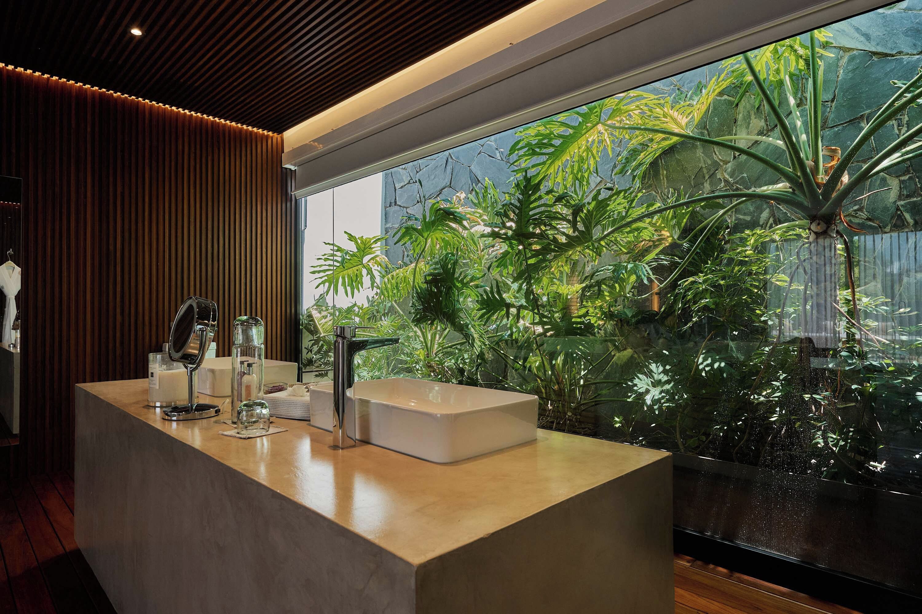Een moderne badkamer met een groot raam, een wastafel en diverse toiletartikelen.