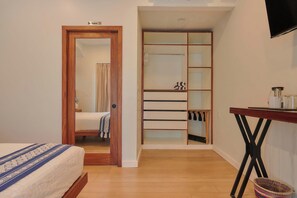 A bedroom with a wooden bed, a wardrobe with a mirror, and a small table with a basket. - Suite in La Punta, a minute from the sand (Puerto Escondido)