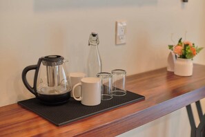 A kitchen counter with a coffee maker, a glass bottle, and two white mugs on a mat. - Suite in La Punta, a minute from the sand (Puerto Escondido)