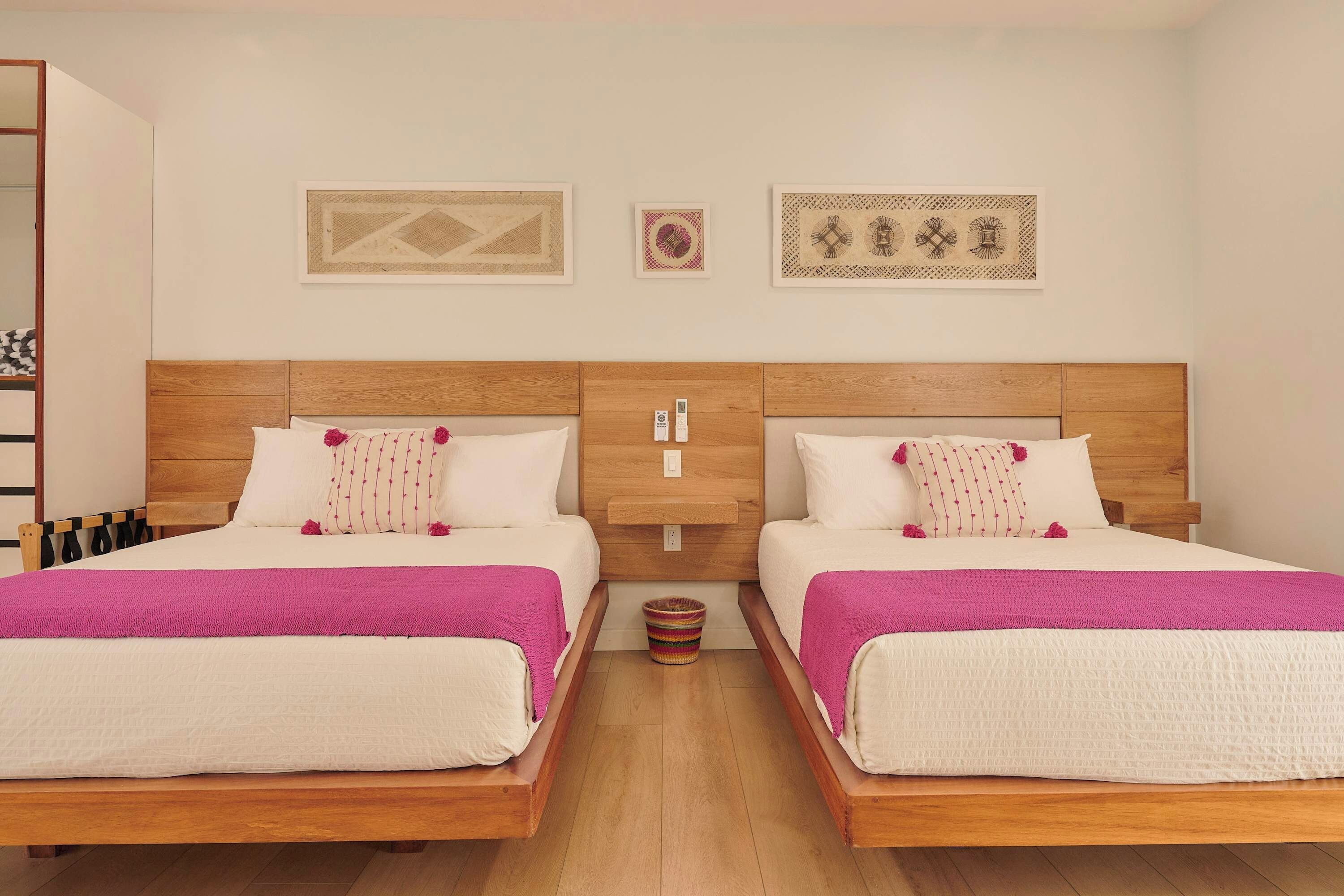 Habitación de hotel con dos camas, cabecero de madera, mesita de noche pequeña y teléfono instalado en la pared.