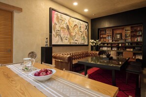 Un comedor con una mesa de madera, un tazón de manzanas y un sofá de cuero.