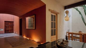Un interior moderno con techo curvo, puerta de madera, un cuadro enmarcado y un comedor con mesa y sillas.