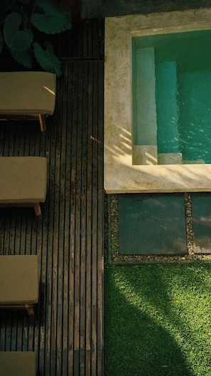 A wooden deck with a pool and lounge chairs.