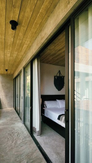 Quarto com cama, uma bolsa pendurada e vista através de portas de vidro.