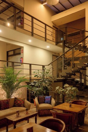 Um hall amplo com escadas, área de estar e plantas.