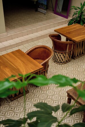 Ein Sitzbereich mit Holztischen und -stühlen, einem gemusterten Boden und einem Blumentopf.
