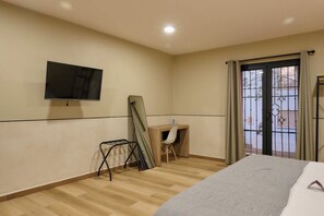 A hotel room with a bed, a desk, a chair, a television mounted on the wall, and a window with curtains. - Charming Oaxaca Suites Near Santo Domingo Temple (Oaxaca de Juárez)
