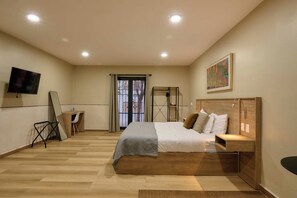 Ein Schlafzimmer mit Bett, Nachttisch, Lampe und einem an der Wand montierten Fernseher.