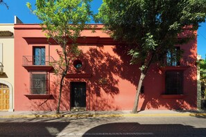 A red building with a balcony, a door, and windows. - Charming Oaxaca Suites Near Santo Domingo Temple (Oaxaca de Juárez)