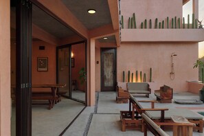 Una hall d'albergo con un'area salotto, una panca di legno, una porta e un muro con dei cactus.