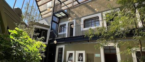 A multi-level atrium with a glass ceiling, indoor plants, and a staircase leading to upper levels.