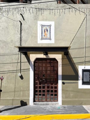 Une façade d’immeuble avec une grande porte en bois, une petite fenêtre et un tableau encadré au-dessus de la porte.